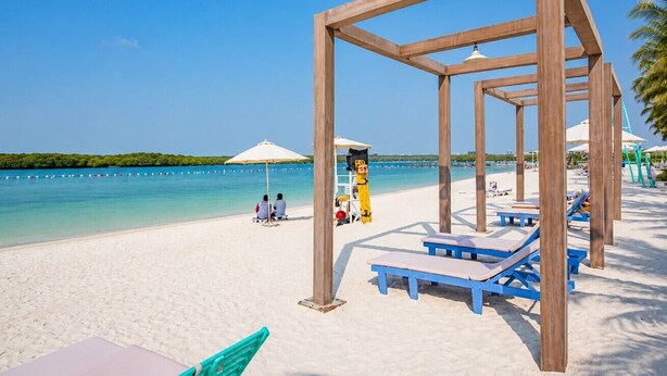 Une plage avec des structures en bois, des chaises longues et des parasols.