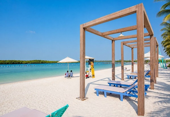 A beach with wooden structures, lounge chairs, and umbrellas.