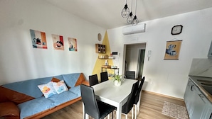 Ein modernes Wohnzimmer mit einer Couch, einem Esstisch, Stühlen und einer Küchenzeile.