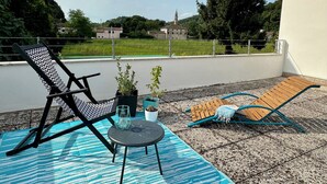 Eine Terrasse mit Gartenmöbeln, einem kleinen Tisch und Topfpflanzen.