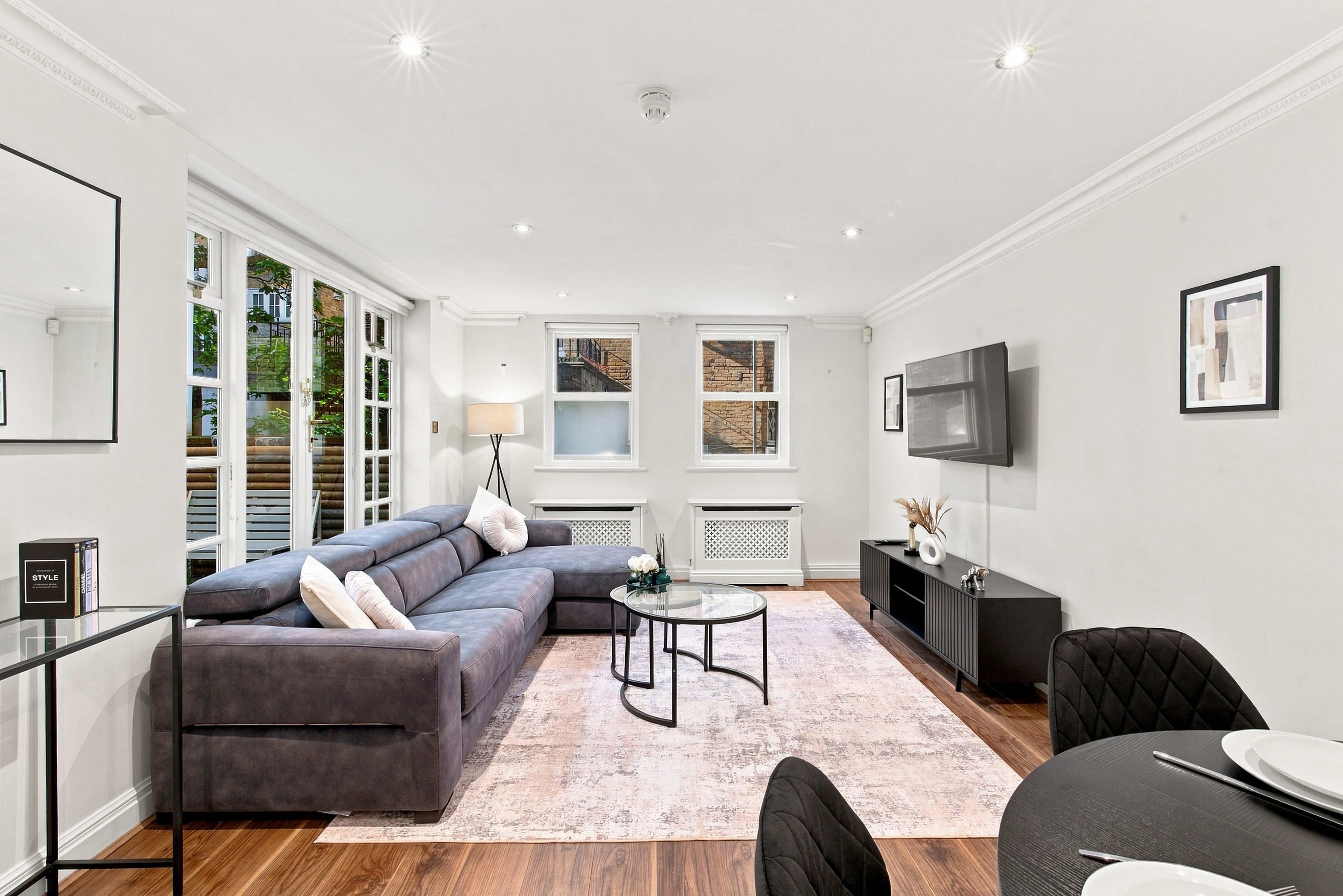 A modern living room with a grey sectional sofa, a round coffee table, and a dining area with a black chair.
