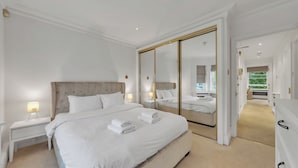 Un dormitorio amplio con una cama grande, un vestidor y una puerta de armario con espejo.