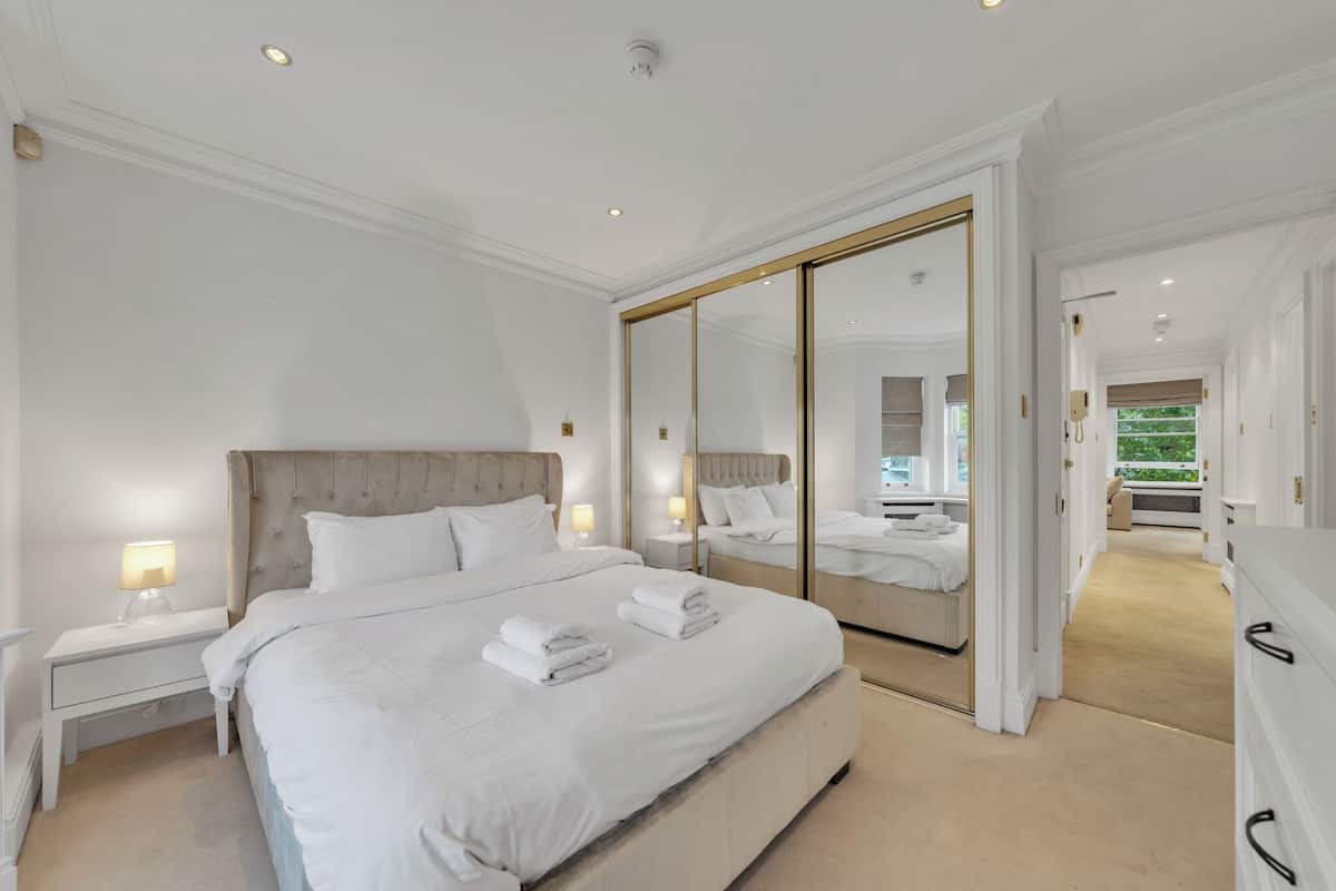 A spacious bedroom with a large bed, a walk-in closet, and a mirrored closet door.