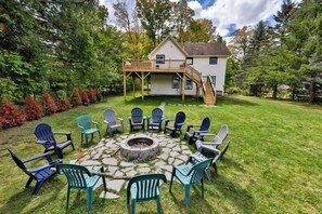 Un jardin avec un foyer extérieur, des sièges de jardin et une maison dotée d’une terrasse.