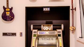 Ein Raum mit Jukebox, Gitarre, Tamburin und einem Schild, das Party-Modus anzeigt.