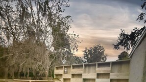 Una terrazza in legno con vasca idromassaggio, circondata da un recinto in legno e alberi.