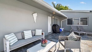 Een terras met een grijze bank, een witte salontafel en een loungestoel.
