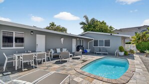 A modern house with a swimming pool, patio furniture, and a covered outdoor seating area.