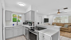 A modern kitchen with white cabinets, a built-in oven, and a large island.