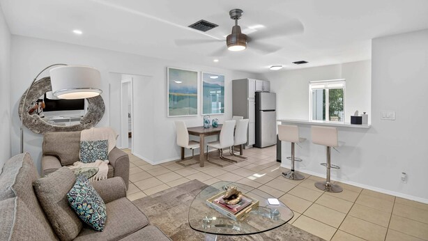 A modern living room with a sofa, coffee table, and a dining area with chairs and a table.