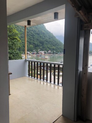 A balcony with a view of a harbor, wooden pillars, and a tiled floor. - Amadeus and Isabel Inn (El Nido)