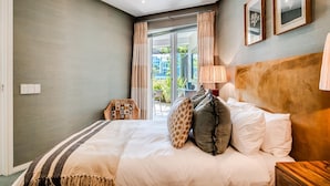 Een slaapkamer met een bed, nachtkastje, lamp en uitzicht op het omliggende landschap.