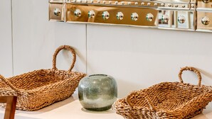 Een wastafel met spiegel, twee gevlochten manden en een glazen pot.