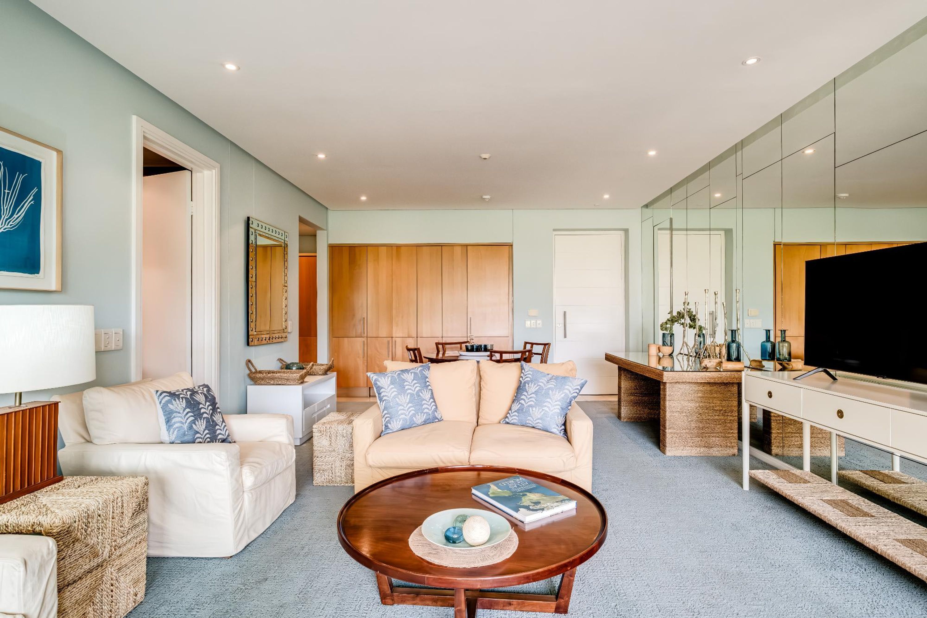 A modern living room with a beige sofa, a coffee table, and a TV.