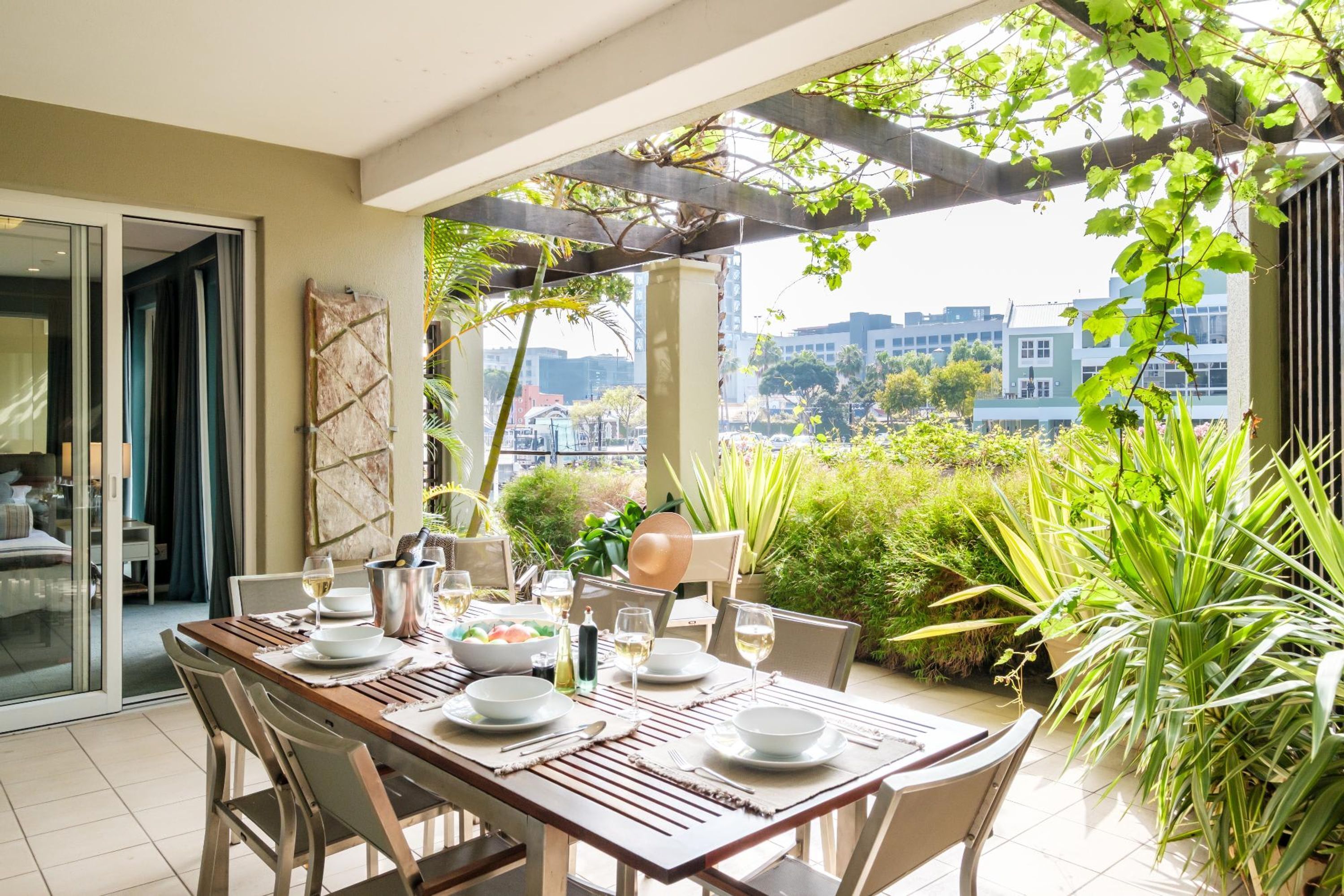 Een eetgedeelte met een tafel voor vier personen, omringd door stoelen, met uitzicht op de stad via een pergola.