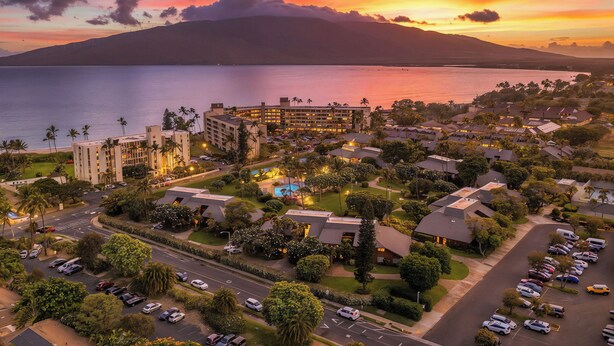 A resort with multiple buildings, a parking area, and a view of the ocean and a mountain. - Stunning Koa Resort Condo | 2Bd/2Ba With A/C | Steps to Beach (Kihei)