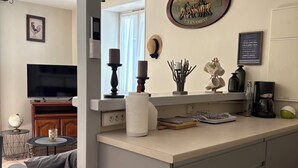 Une cuisine moderne avec un îlot central, un coin repas avec un canapé et un téléviseur dans le salon.