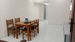 A dining area with a wooden table and chairs, a pitcher, and a glass.