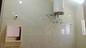 A bathroom with a shower, a toilet, and a mirror.