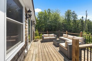 A wooden deck with outdoor furniture, a railing, and a view of trees. - Serene Pondside Cottage w/Private Island Camping! (Blue Hill)