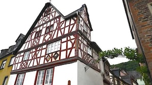 A traditional half-timbered building with a steeply pitched roof, multiple windows, and a visible chimney.
