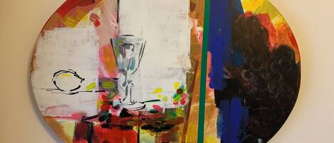 A circular artwork with abstract and colorful elements, including a vase and flowers.