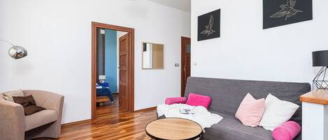 Una sala de estar moderna con un sofá gris, una mesa de centro redonda de madera y un sillón beige.