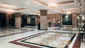 Eine geräumige Lobby mit Marmorboden, großen Säulen und Kronleuchtern.