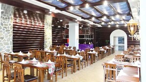 Un restaurante con mesas y sillas de madera, una pared de piedra y un techo con diseño que simula el cielo.