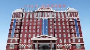 Un edificio grande de ladrillo rojo con una fachada simétrica, numerosas ventanas y una entrada central con un frontón decorativo.