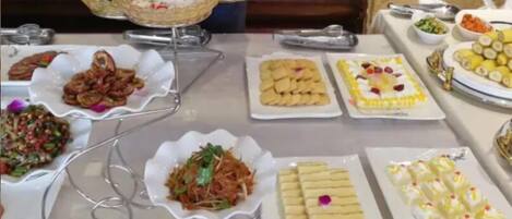 Una mesa de buffet con diversos platos, como ensaladas, aperitivos y postres.