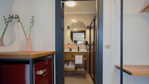 A narrow hallway leading to a bathroom with a mirror, sink, and towel rack.