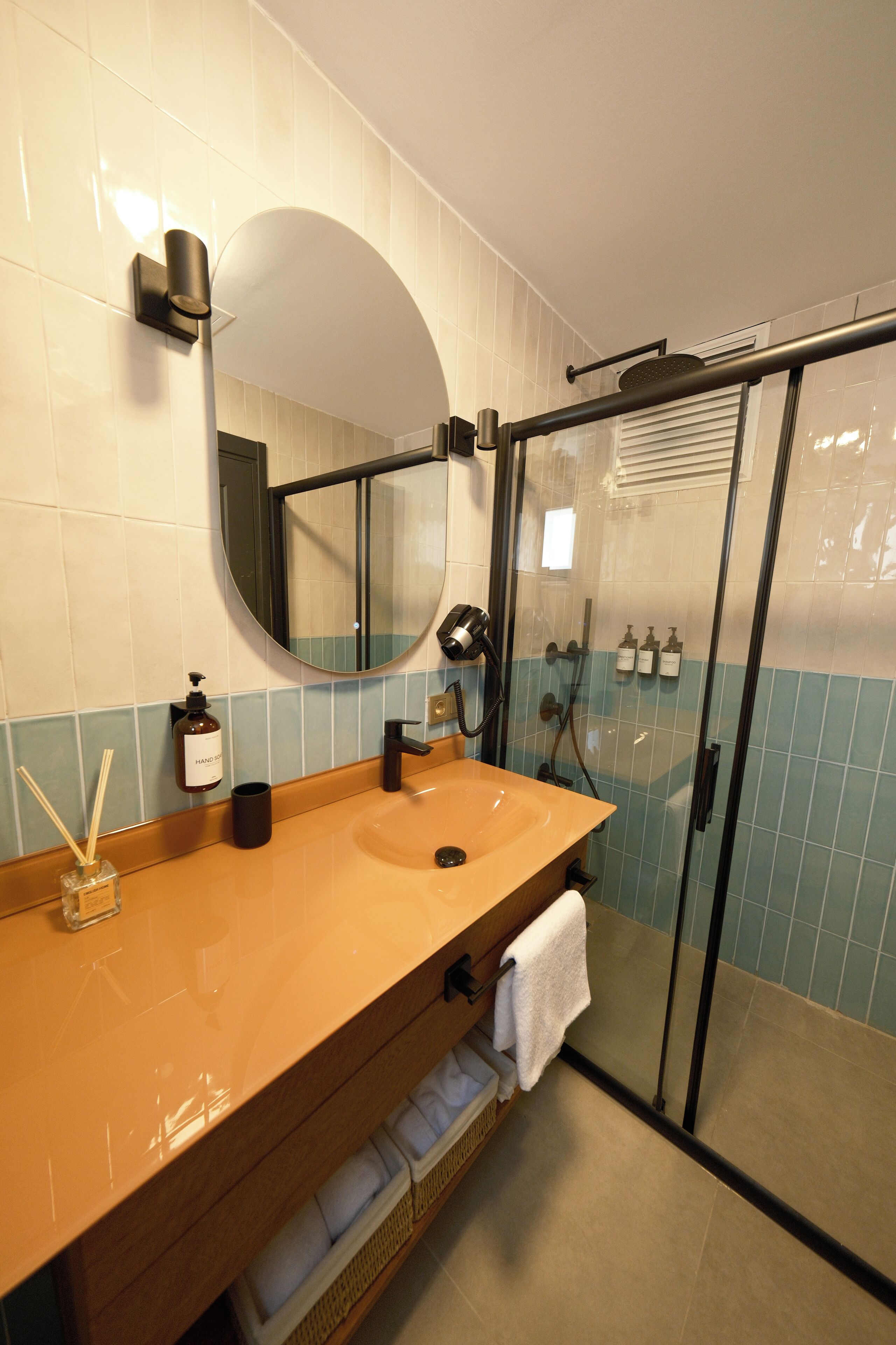 Un baño moderno con tocador de madera, un espejo grande, cabina de ducha de vidrio y un perchero para toallas.