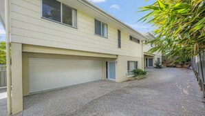 Un immeuble résidentiel de deux étages, doté d’un garage, d’une allée et d’un petit jardin.