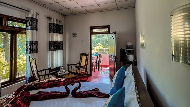 A hotel room with a large bed, two chairs, a small table, and a view of the outdoors. - Willow Cottage Ella (Ella)