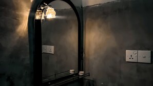 A bathroom with a white sink, a mirror with an arch, and a light fixture above the mirror. - Willow Cottage Ella (Ella)