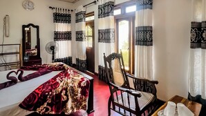 A hotel room with a bed, a wooden chair, a small table with cups, a mirror, and a clock on the wall. - Willow Cottage Ella (Ella)