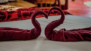 A bed with a heart-shaped towel arrangement on the floor. - Willow Cottage Ella (Ella)
