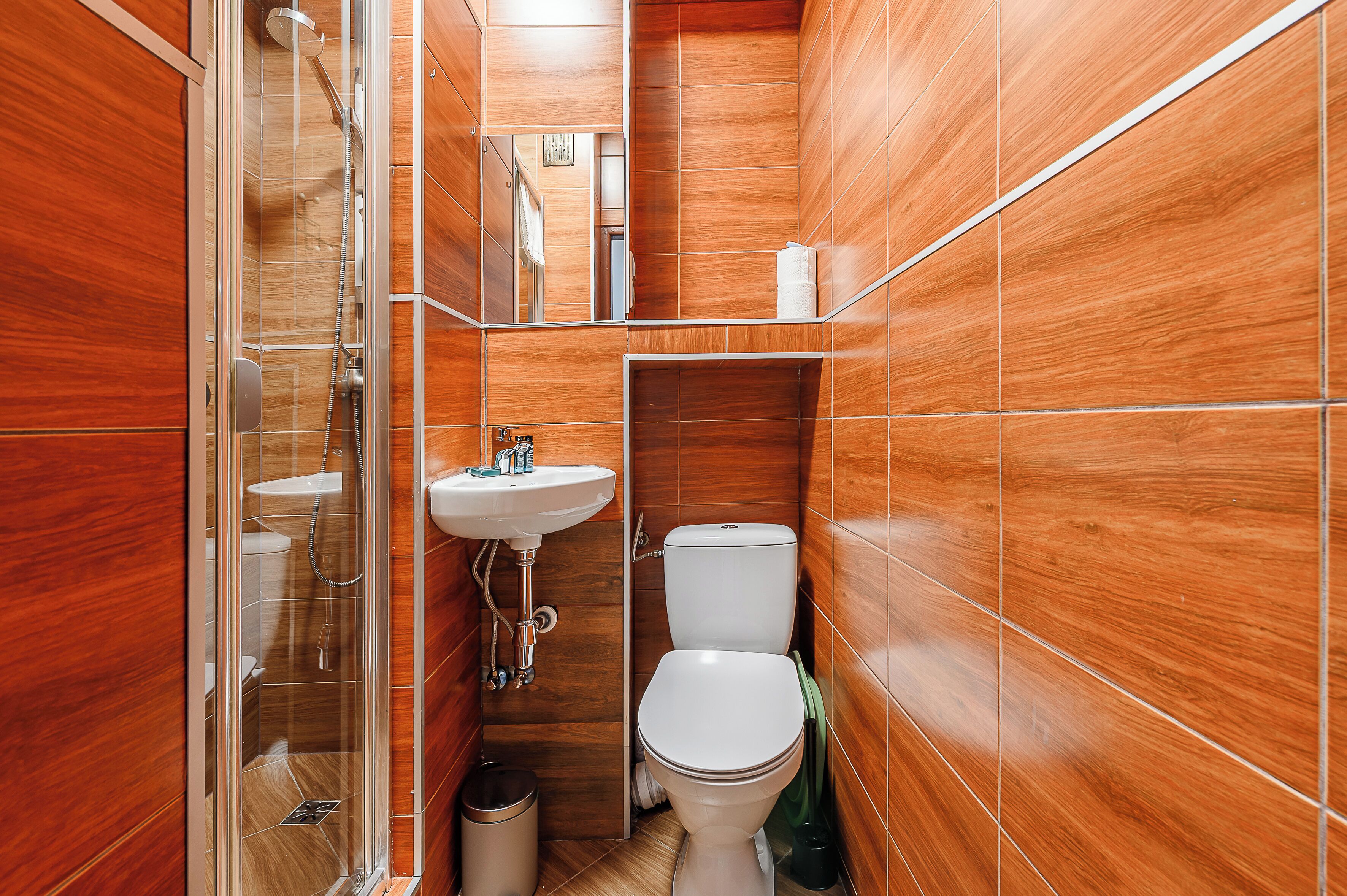 Un baño con ducha de mampara de vidrio, lavamanos y retrete.