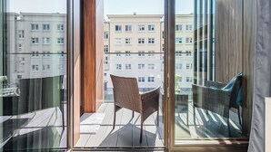 Parvekkeella on rottinkituoleja, lasiovi ja näkymä viereisiin rakennuksiin.