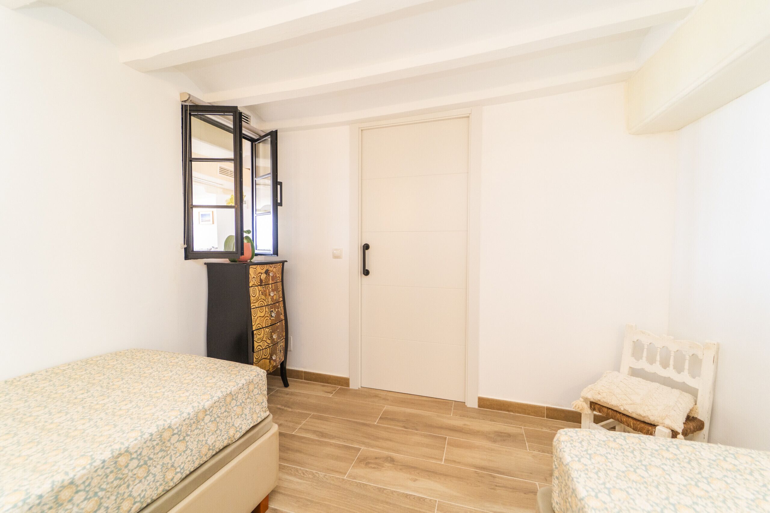 A bedroom with two beds, a dresser, a mirror, and a door.