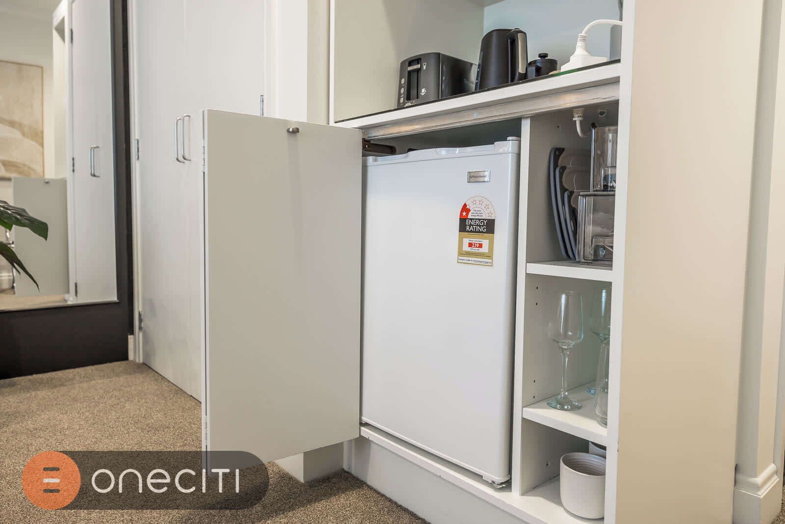 A compact kitchen with a white refrigerator, a microwave, and a coffee maker on the countertop.