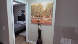 Un dormitorio con una cama, un cuadro y un jarrón en el suelo.