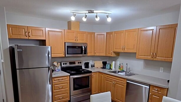 Una cocina moderna con armarios de madera, electrodomésticos de acero inoxidable y una mesa de comedor de vidrio.