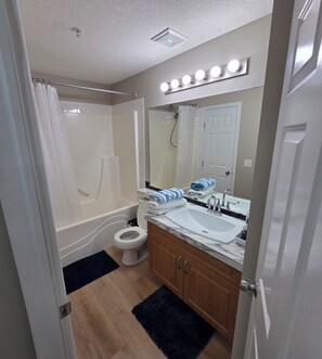A bathroom with a bathtub, toilet, sink, and vanity.