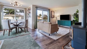 A modern living room with a sofa, dining table, and chairs, a TV, and a fireplace.