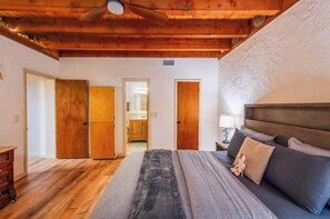 A bedroom with a bed, wooden doors, a ceiling fan, and a nightstand with a lamp.