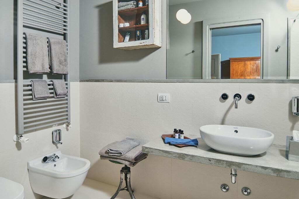 A bathroom with a white sink, a bidet, a towel rack, a mirror, and a medicine cabinet.