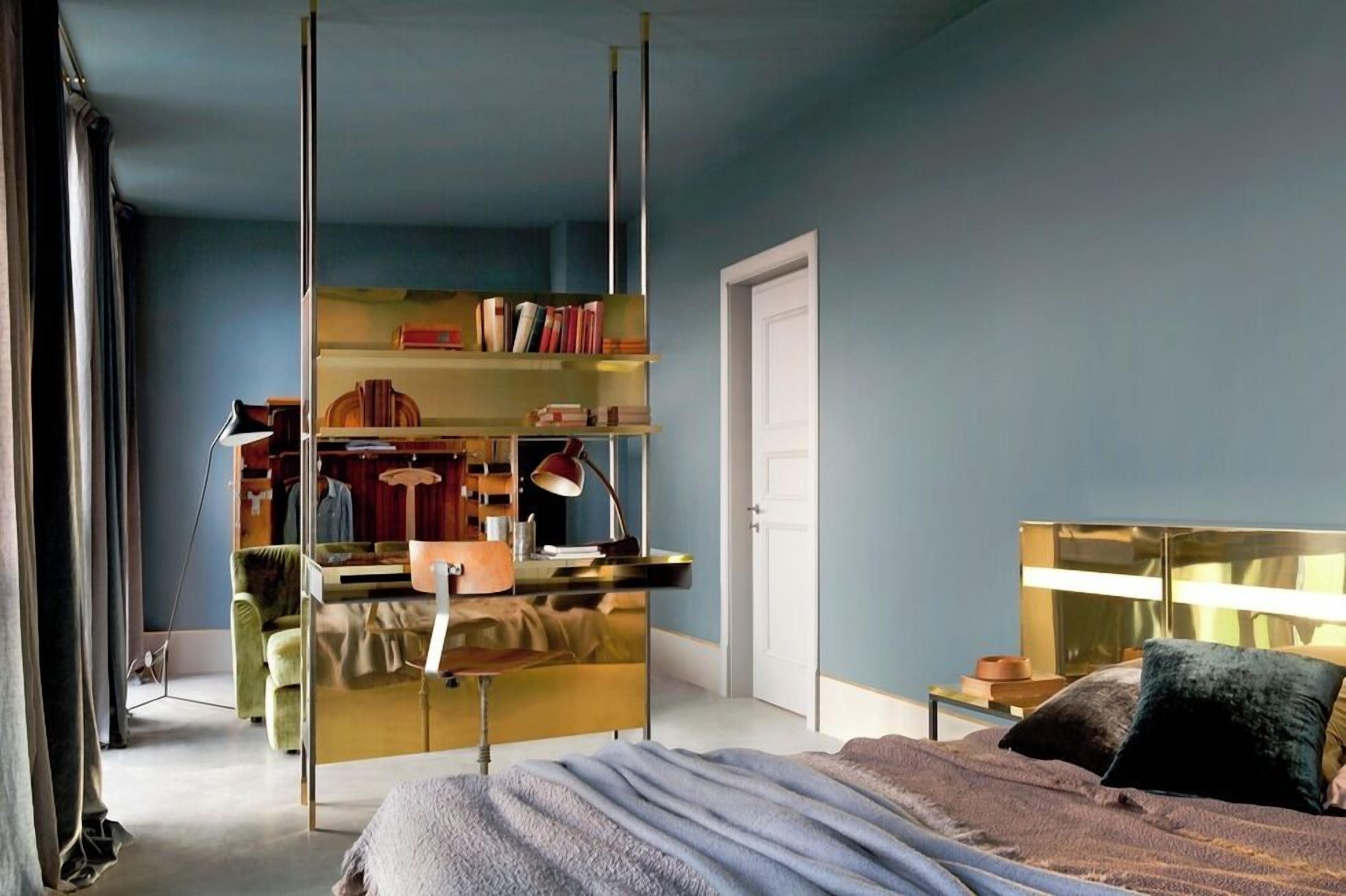 Une chambre à coucher comprenant un lit, une table de chevet, un miroir, une armoire et une bibliothèque.