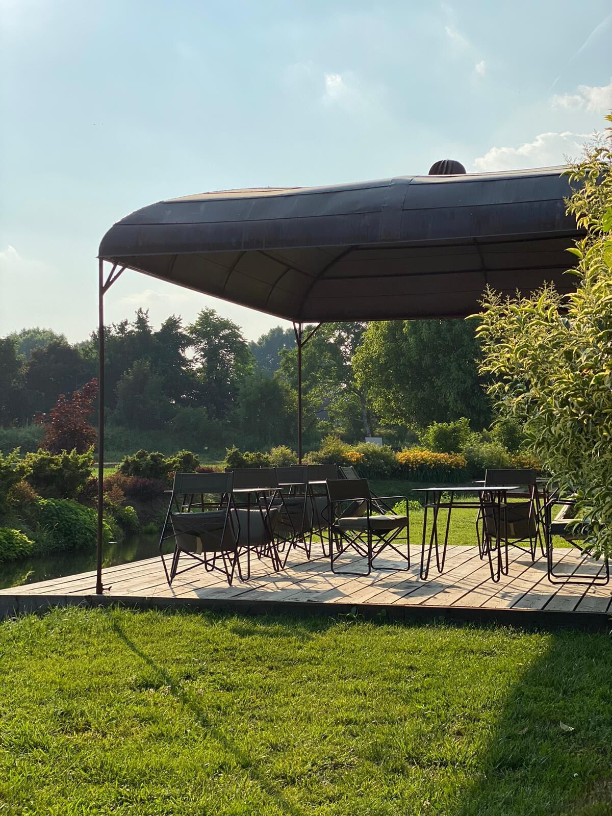 Een terras buiten met een tafel en stoelen onder een grote overkapping.